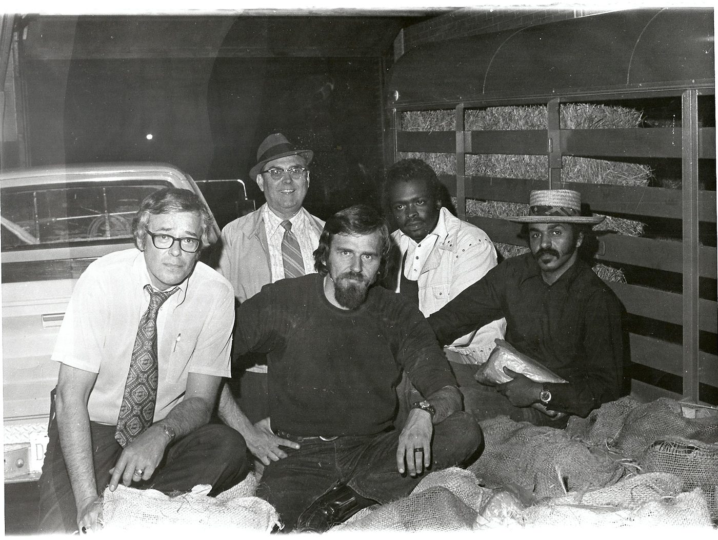 Plainclothes men gathered in a truck bed at night